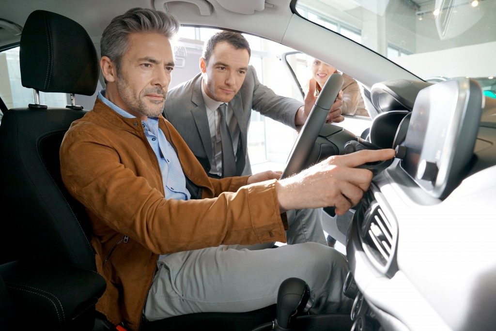 Man checking the specs of a car with car salesman