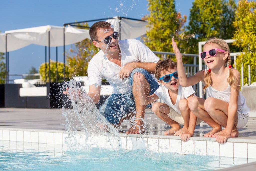 father with kids having fun in the pool