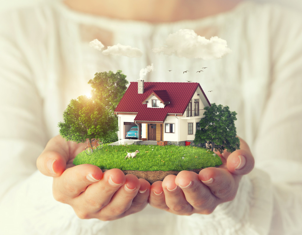 woman holding miniature house with plants and trees