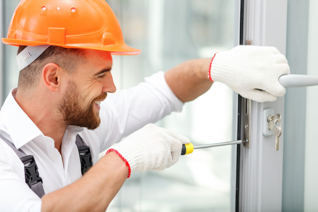 smiling young worker installing new door lock